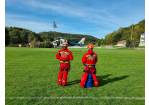 Fotografie: Höhenretter warten auf einen landenden Hubschrauber auf einem Sportplatz.