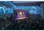 Fotografie – Konzert im blau beleuchteten Innenhof des Thon-Dittmer-Palais in Regensburg, Zuhörende und beleuchtete Bühne