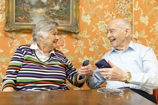 Fotografie: Zwei ältere Leute halten Handys in der Hand.