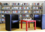Foto zwei Sessel und ein Tisch. Im Hintergrund Bücherregale