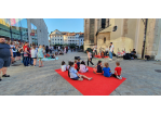Kinder sitzen auf einem roten Teppich auf dem Kassiansplatz und hören der Band zu