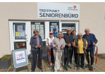 Fotografie - Senior/innen mit Nordic Walking Stöcken vor dem Treffpunkt Seniorenbüro