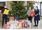 Fotografie - drei Personen neben einem Weihnachtsbaum mit Geschenken