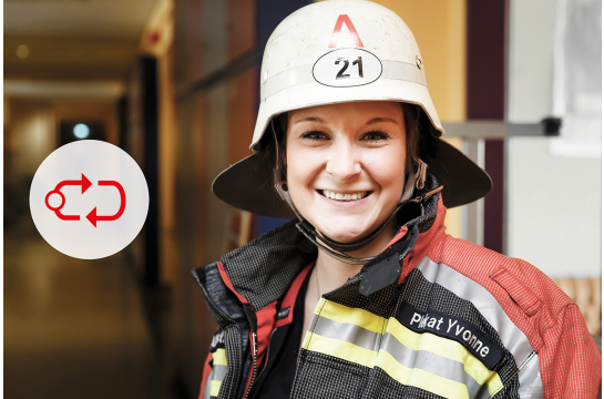 Feuerwehrfrau in Ausrüstung lacht in die Kamera