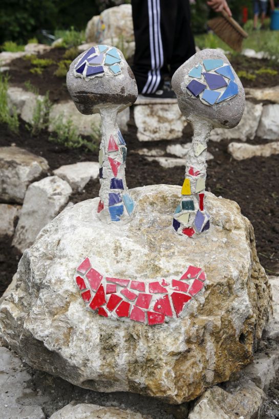 Fotografie - Rasentier Schnecke, gebaut aus großen Steinen, Gesicht gestaltet mit bunten Mosaiksteinen