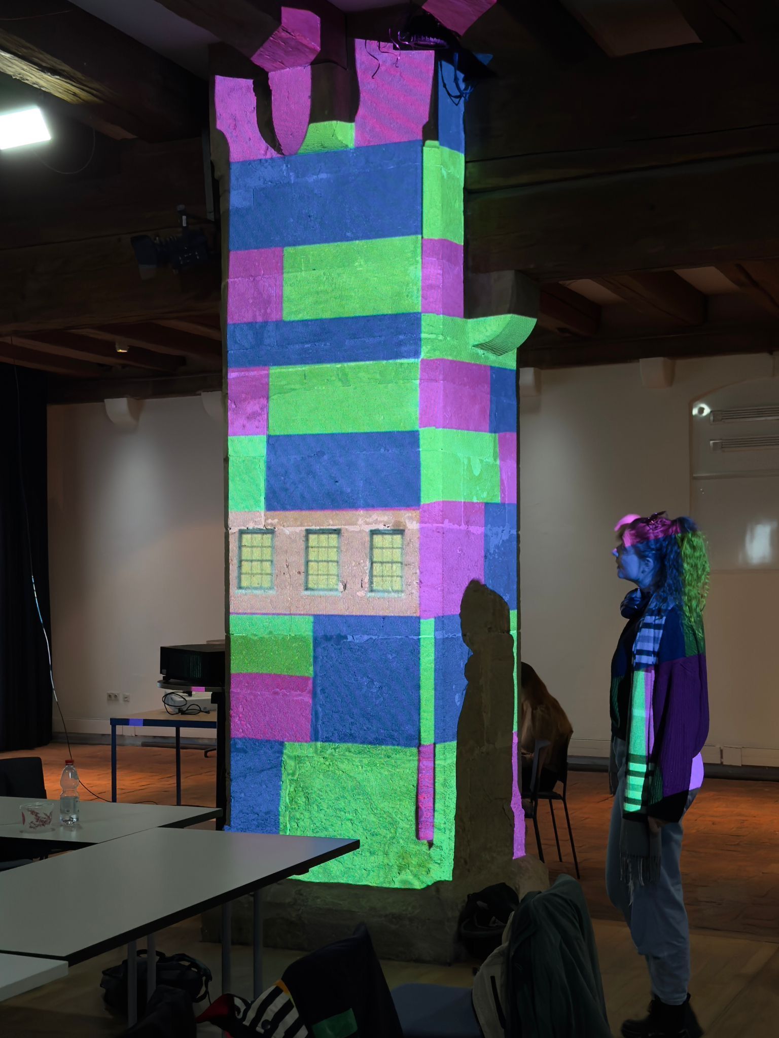 Fotografie – Eine Säule wird in bunten Lichtern als Turm angestrahlt