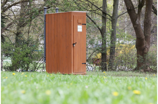 Fotografie: Komposttoilettenhäuschen aus Holz auf einer Wiese