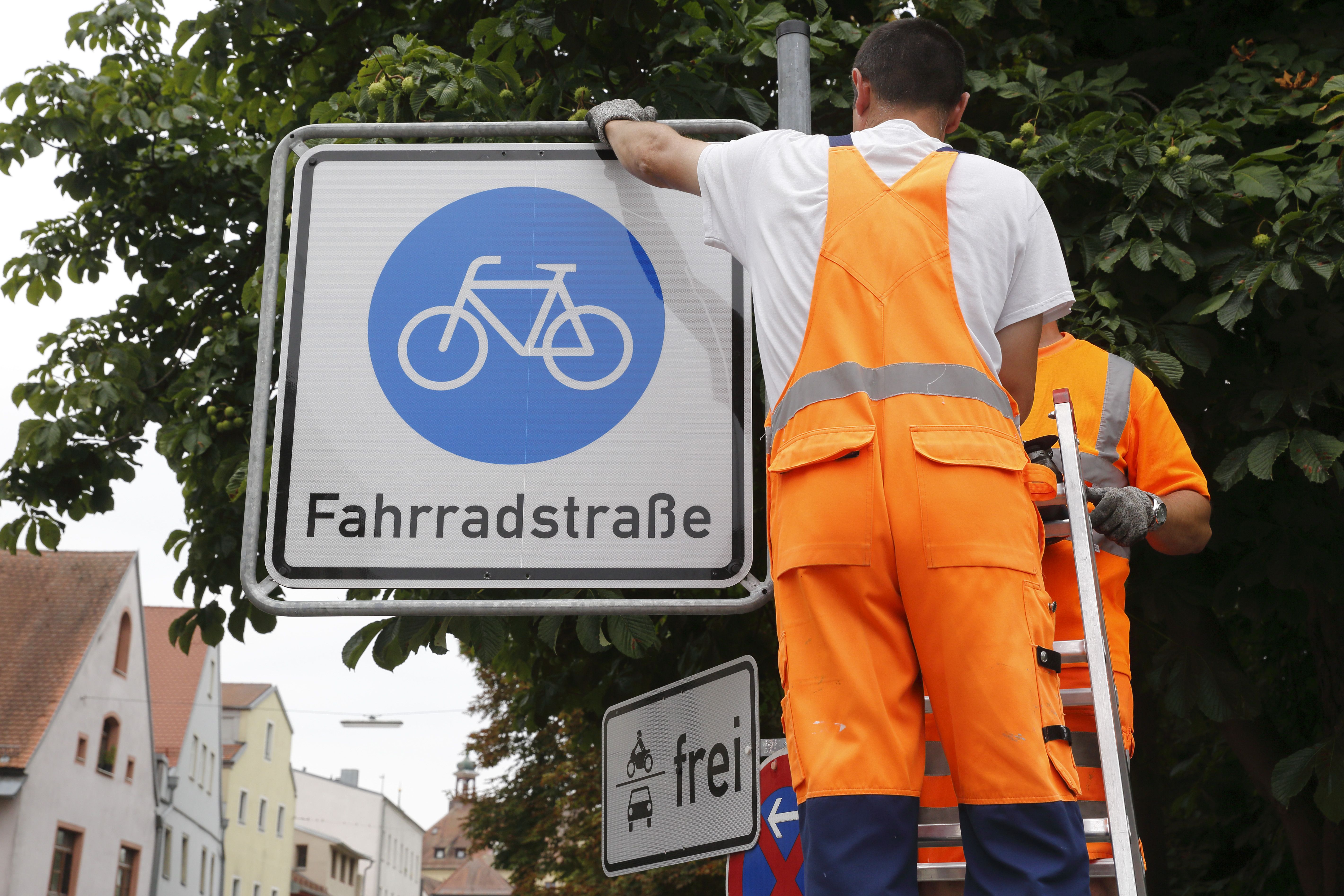 Mitarbeiter der Stadt Regensburg bringen das Verkehrsschild "Fahrradstraßen" an.