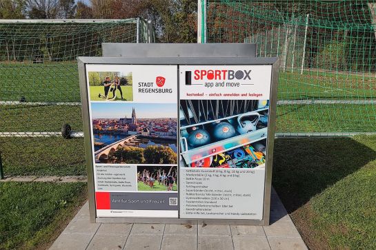 Fotografie - Sportbox auf einem Sportplatz, dahinter Fußballtore