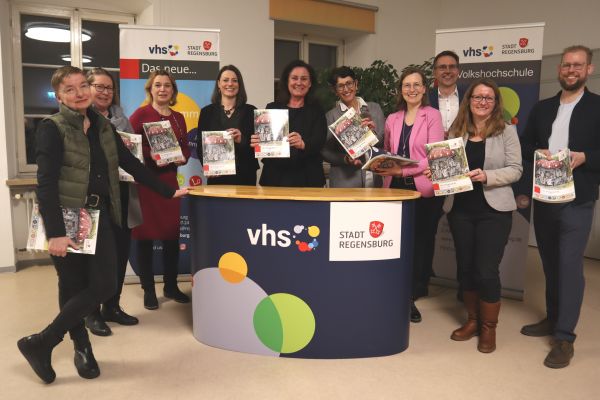 Fotografie: Dr. Ute Eiling-Hütig, Präsidentin des Bayerischen Volkshochschulverbandes (bvv) und MdL (5. v. l.), und die bvv-Vorstände, Dr. Christian Hörmann (3. v. r.) und Dr. Regine Sgodda (4. v. r.), freuten sich mit Bildungsreferentin Dr. Sabine Kellner-Mayrhofer (5. v. r.) und Nina Dollinger-Krome, Leiterin des Amtes für Weiterbildung und der Volkshochschule (4. v. l.), mit vhs-Mitarbeitenden über das druckfrische Programm.