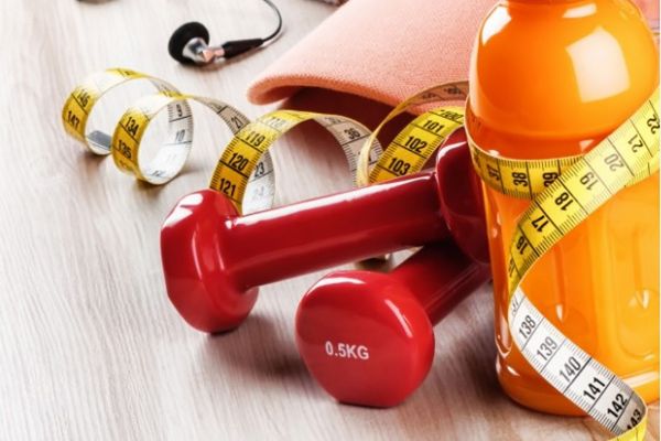 Symbolbild: Turnschuhe, Handtücher, Trinkflaschen und weiteres Fitnesszubehör auf dem Boden drapiert