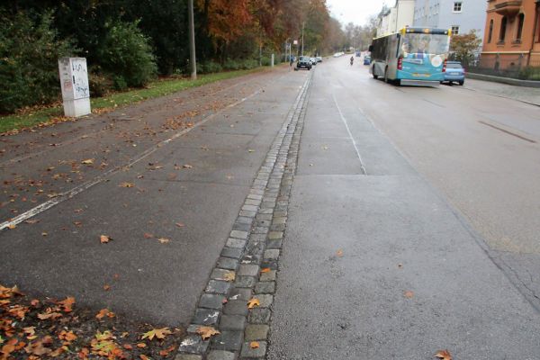 Prüfeninger Straße - Fotografie - im linken Bildbereich sieht man eine 3-zeilige Rinne aus Granitgroßsteinen, die große Schäden aufweist 