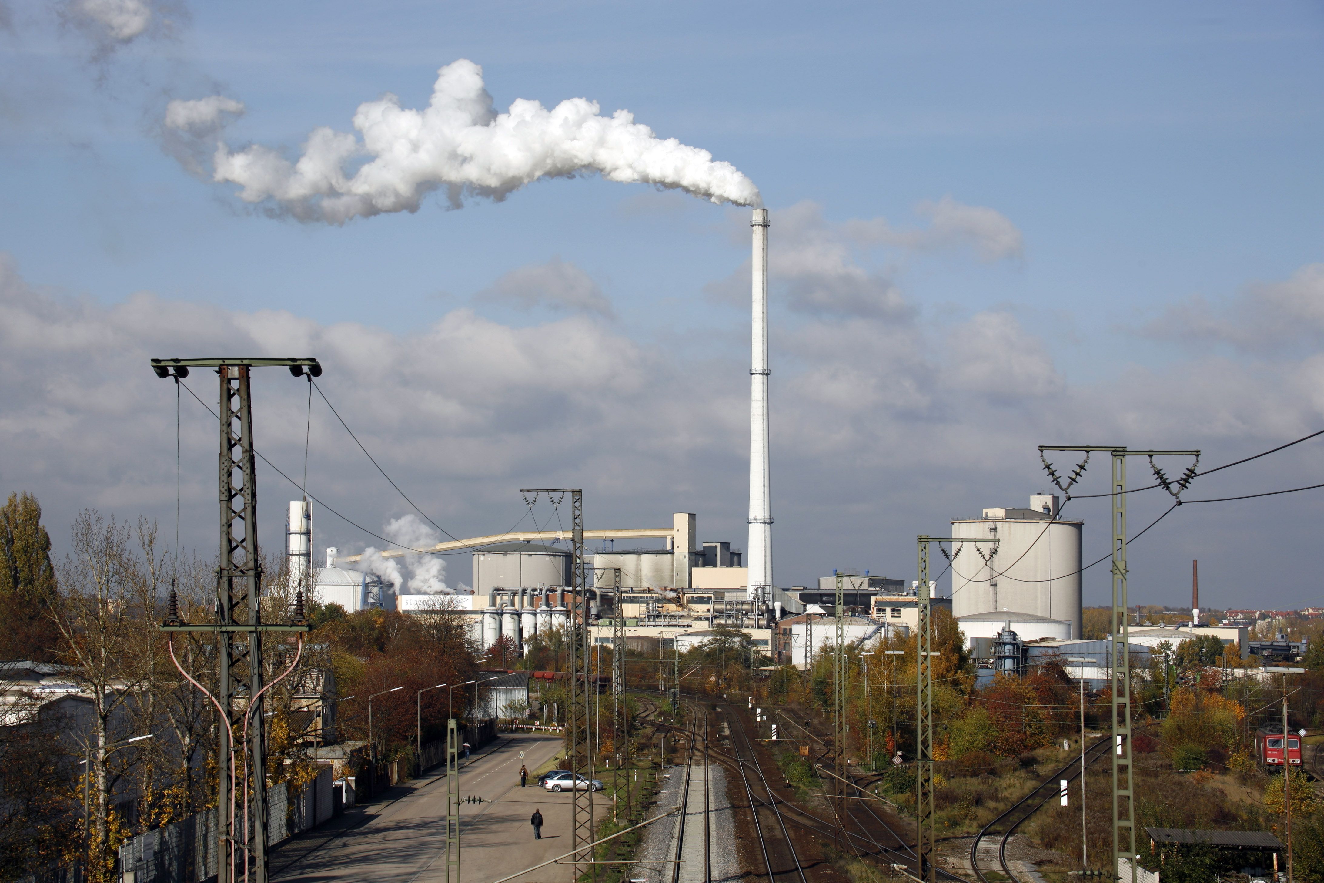 Fotografie: Blick über Gleise auf die ehemalige Zuckerfabrik mit qualmendem Schornstein