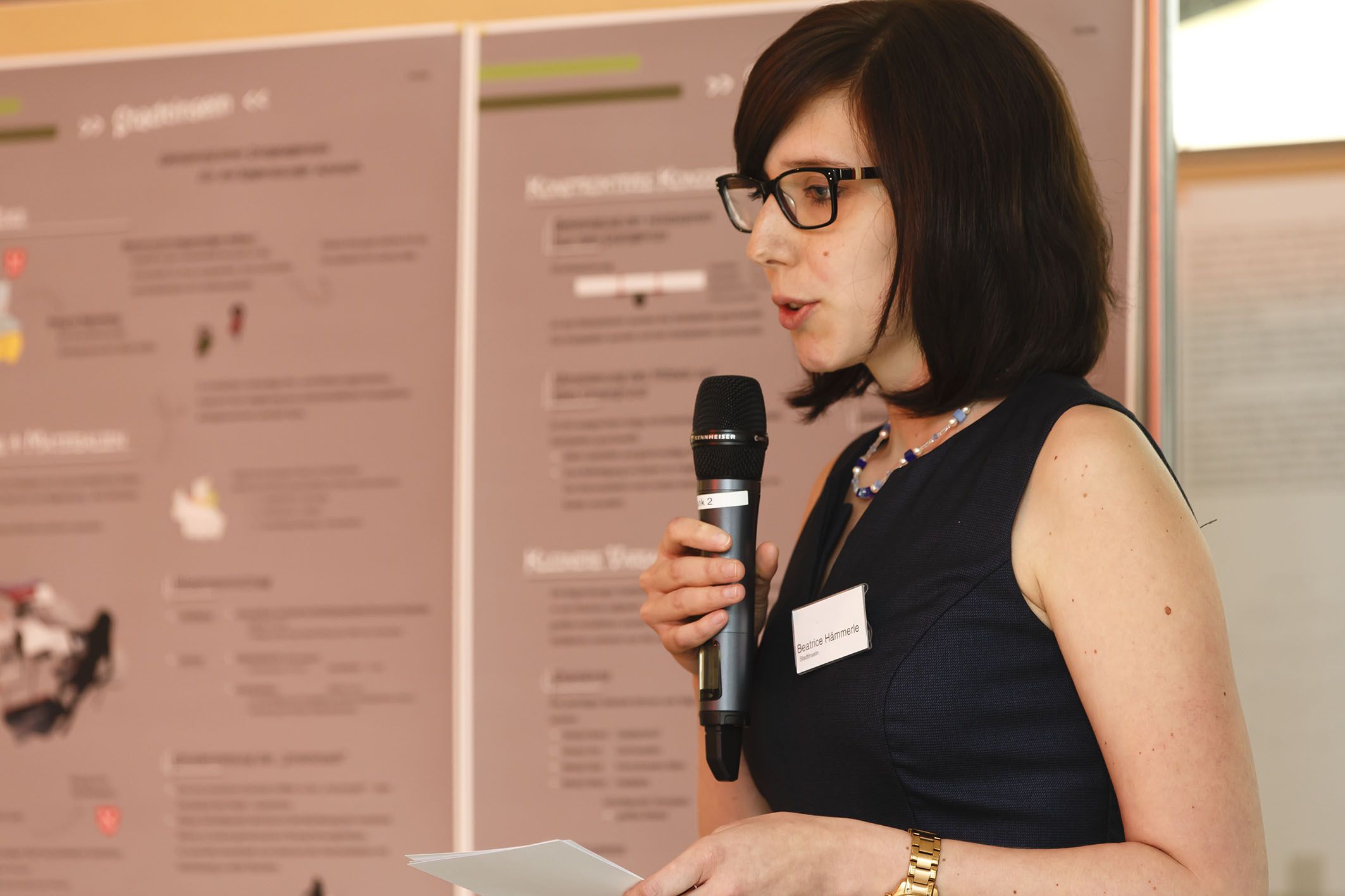 Aktion Sondermöbel - Foto einer Veranstaltung - am Mikrofon vor einer Infowand Beatrice Hämmerle