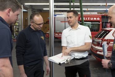 Fotografie: Christoph Tresch erklärt den Kollegen Unterlagen in einem Ordner.