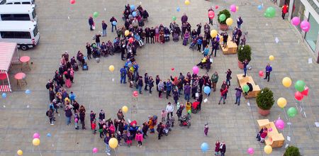 Themenbild Menschen mit Behinderung - Luftaufnahme - Menschen mit und ohne Behinderung die Luftballons steigen lassen