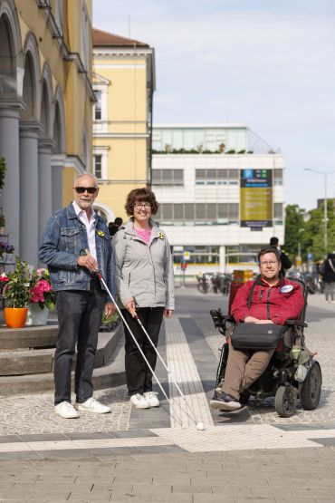 Fotografie: Der Inklusionsbeauftragte der Stadt Regensburg, Frank Reinel, zusammen mit der Bezirksgruppenleiterin des BBSB e. V., Bettina Pichlmeier und deren Ehemann Rudolf, bei der Besichtigung des taktilen Leitsystems vor dem Hauptbahnhof Regensburg
