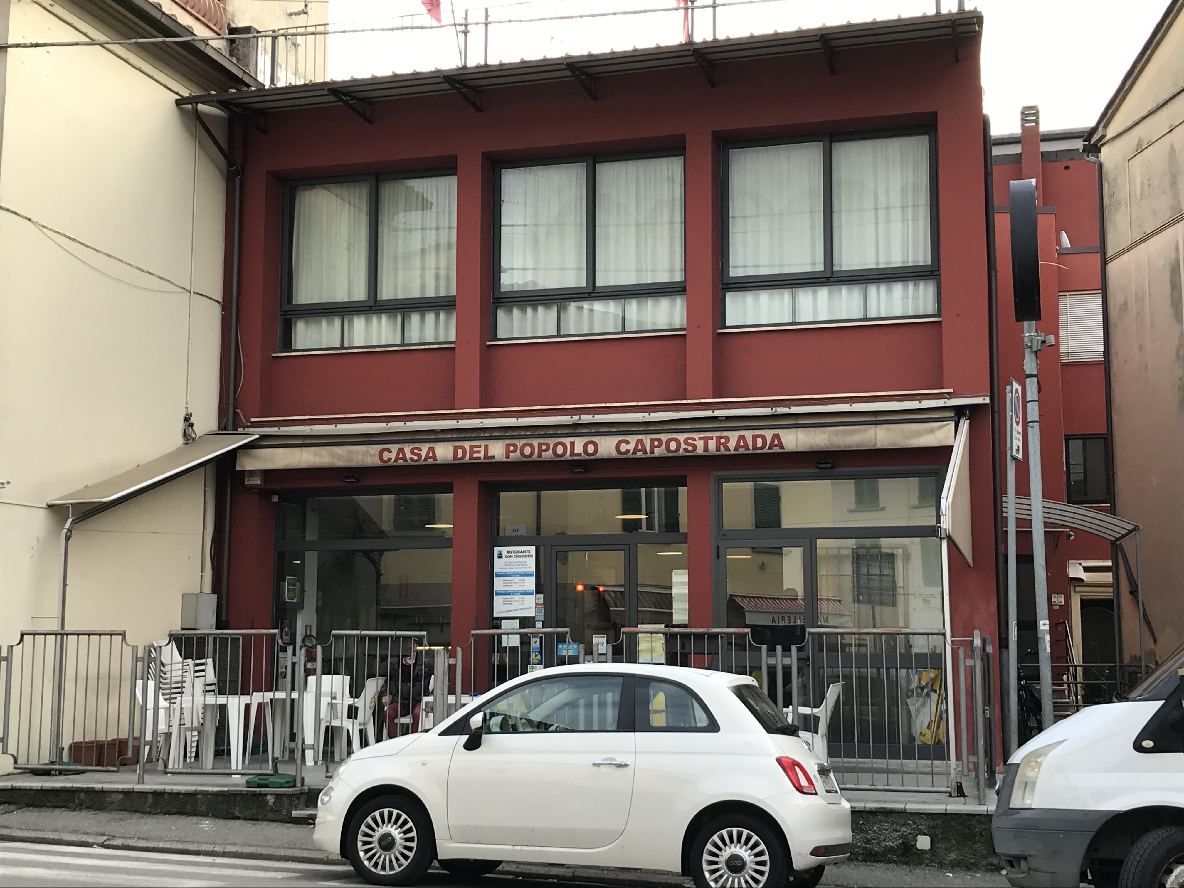 Gaststätte in Italien; davor Straße mit Auto