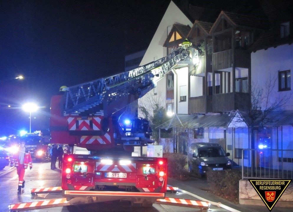 Fotografie: Drehleiterfahrzeug der Berufsfeuerwehr Regensburg vor einem Mehrfamilienhaus bei der Durchführung einer Personenrettung.