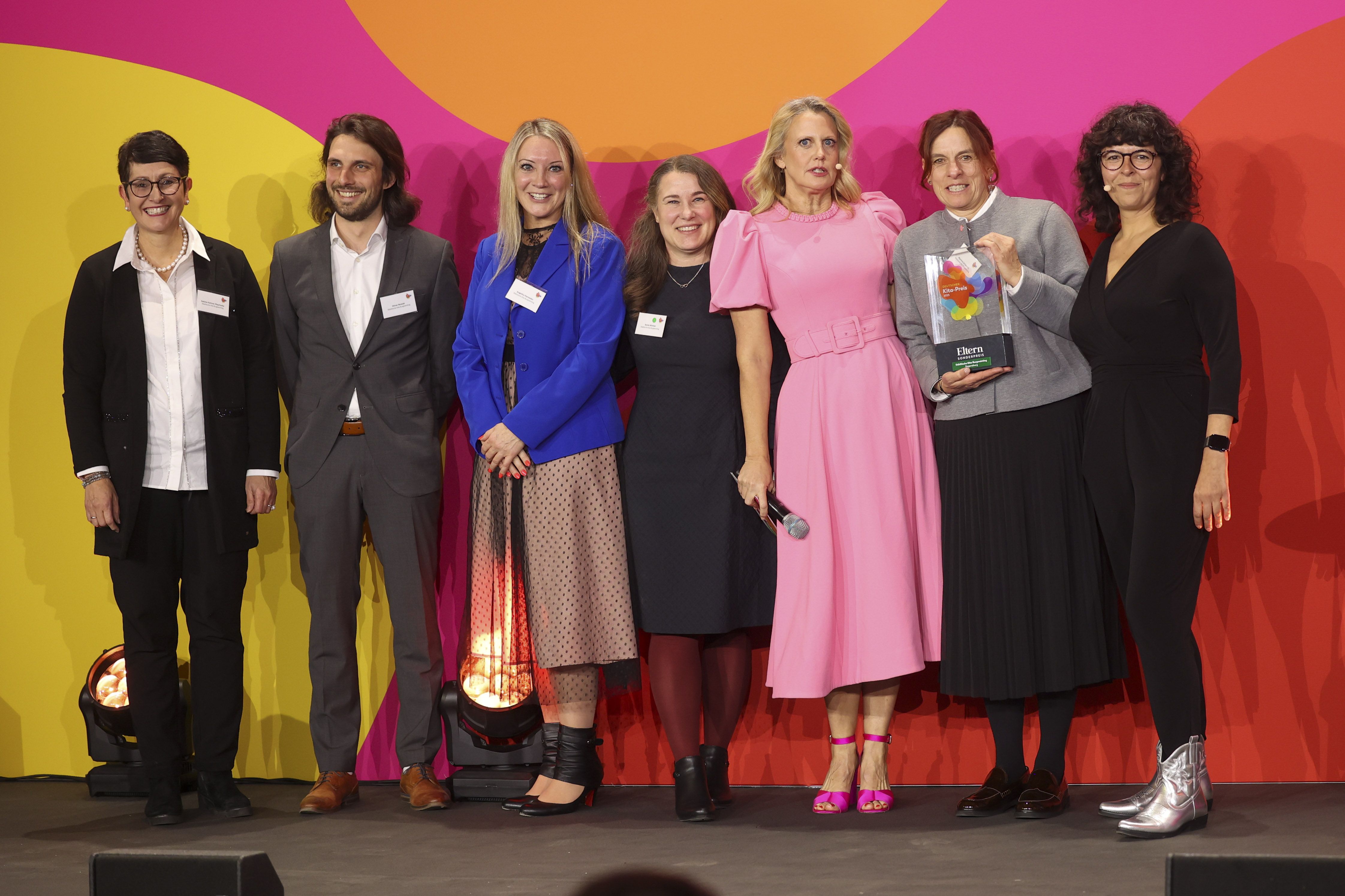 Fotografie – v.l.: Bildungsreferentin Dr. Sabine Kellner-Mayrhofer, Oliver Nowak, Leiter des Amtes für Tagesbetreuung von Kindern, Angelika Hanseder, Sylvia Winkler und Martina Scheuchl als Vertreterinnen der Kita mit Moderatorin Barbara Schöneberger (3.v.r.) und Biona Schütt, Redaktionsleiterin bei ELTERN (r.). 