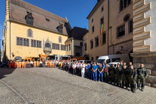 Fotografie – Beschäftigte der Stadt Regensburg aus verschiedenen Ämtern mit ihren Dienstfahrzeugen, im Hintergrund das Alte Rathaus