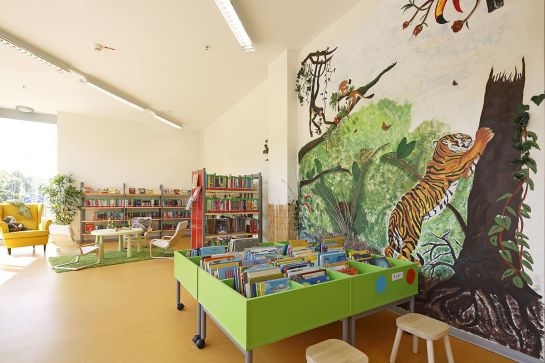 Container und Buchregale mit Kinderbüchern, Wandgemälde Dschungel