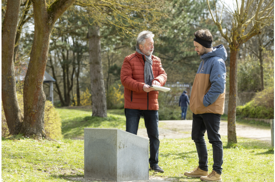 Fotografie: Stadtheimatpfleger Prof. Gerhard Waldherr erläutert einem Mann am Kumpfmühler Geschichtsquader die spannende Geschichte des ehemaligen römischen Kohortenlagers.