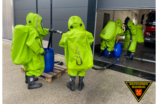 Fotografie: Einsatzkräfte der Feuerwehr mit Chemikalienschutzanzügen bei einer Übung.