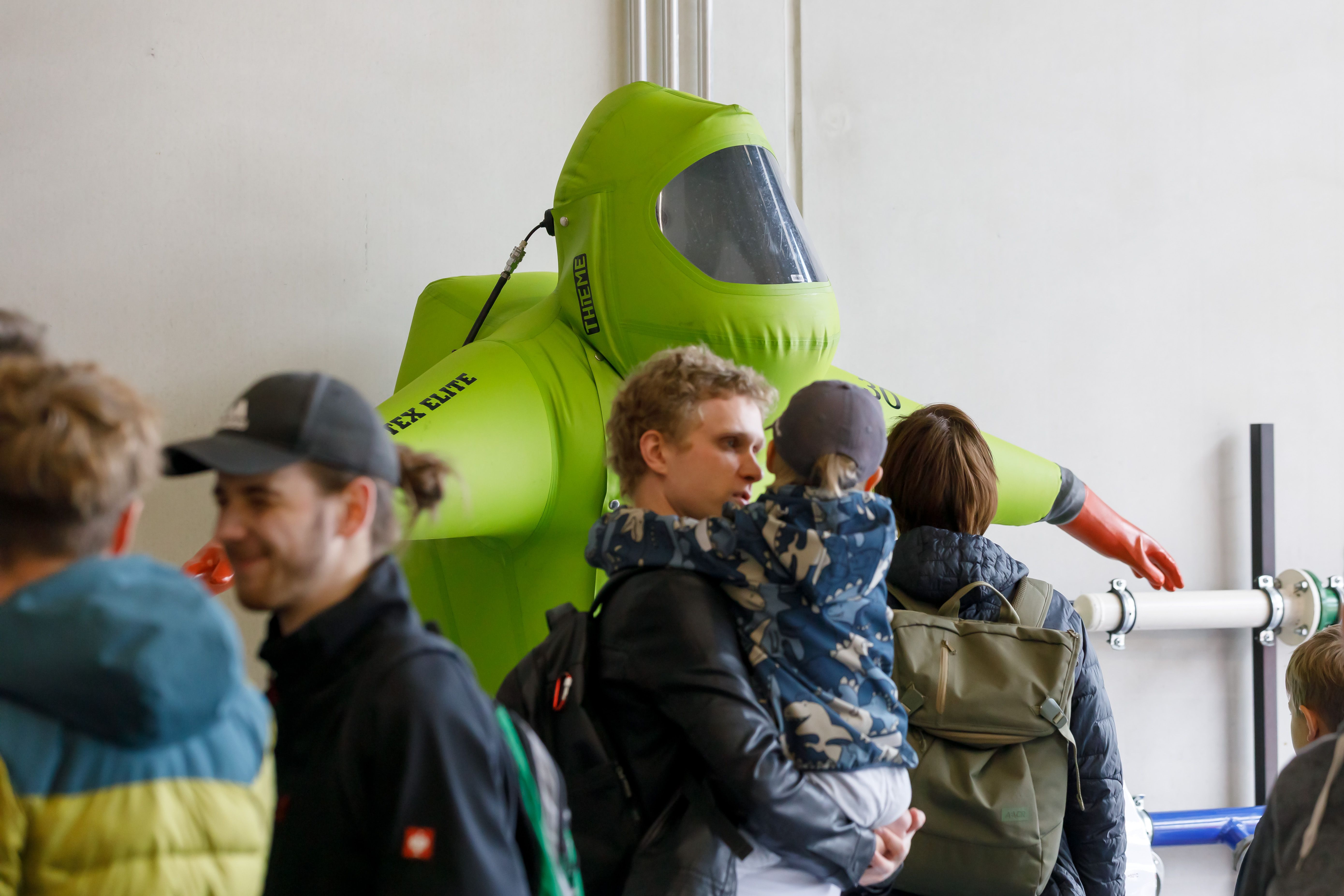 Fotografie: Die Besucher betrachten Schutzkleidung.