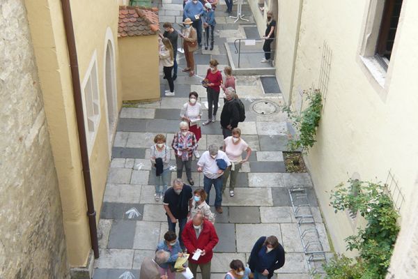 Fotografie - Menschen stehen im Innenhof des Runtingerhauses in einer Schlange an