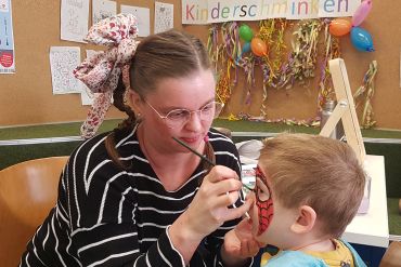 Eine Frau schminkt einen Jungen.