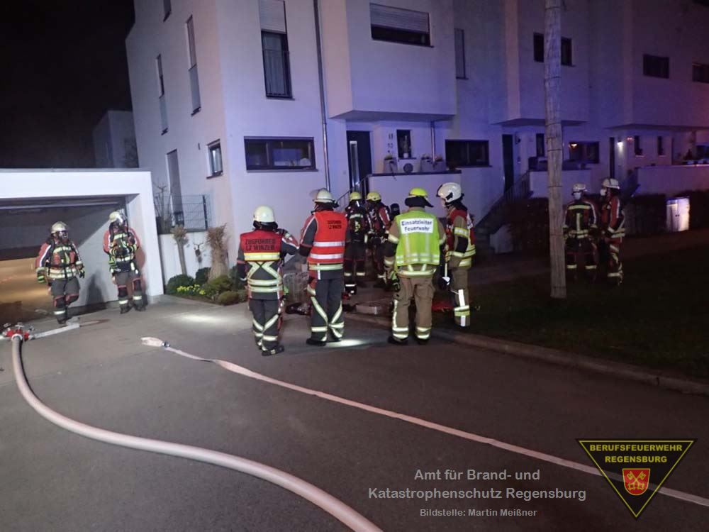Einsatzkräfte der Feuerwehr vor einer Tiefgarage.
