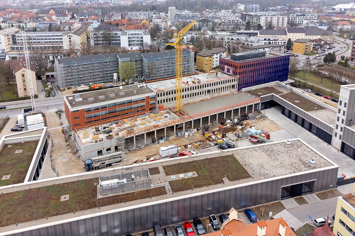 Fotografie - Baustelle mit dem Rohbau und den bereits fertiggestellten Gebäuden