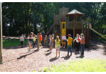 Fotografie – Kinder aus der Gruppe der Kinderberaterinnen und Kinderberater stehen im Kreis und beraten gemeinsam mit den städtischen Mitarbeiterinnen darüber, wie der neu zu bauende Spielplatz gestaltet werden könnte (C) Lena Schwaiger
