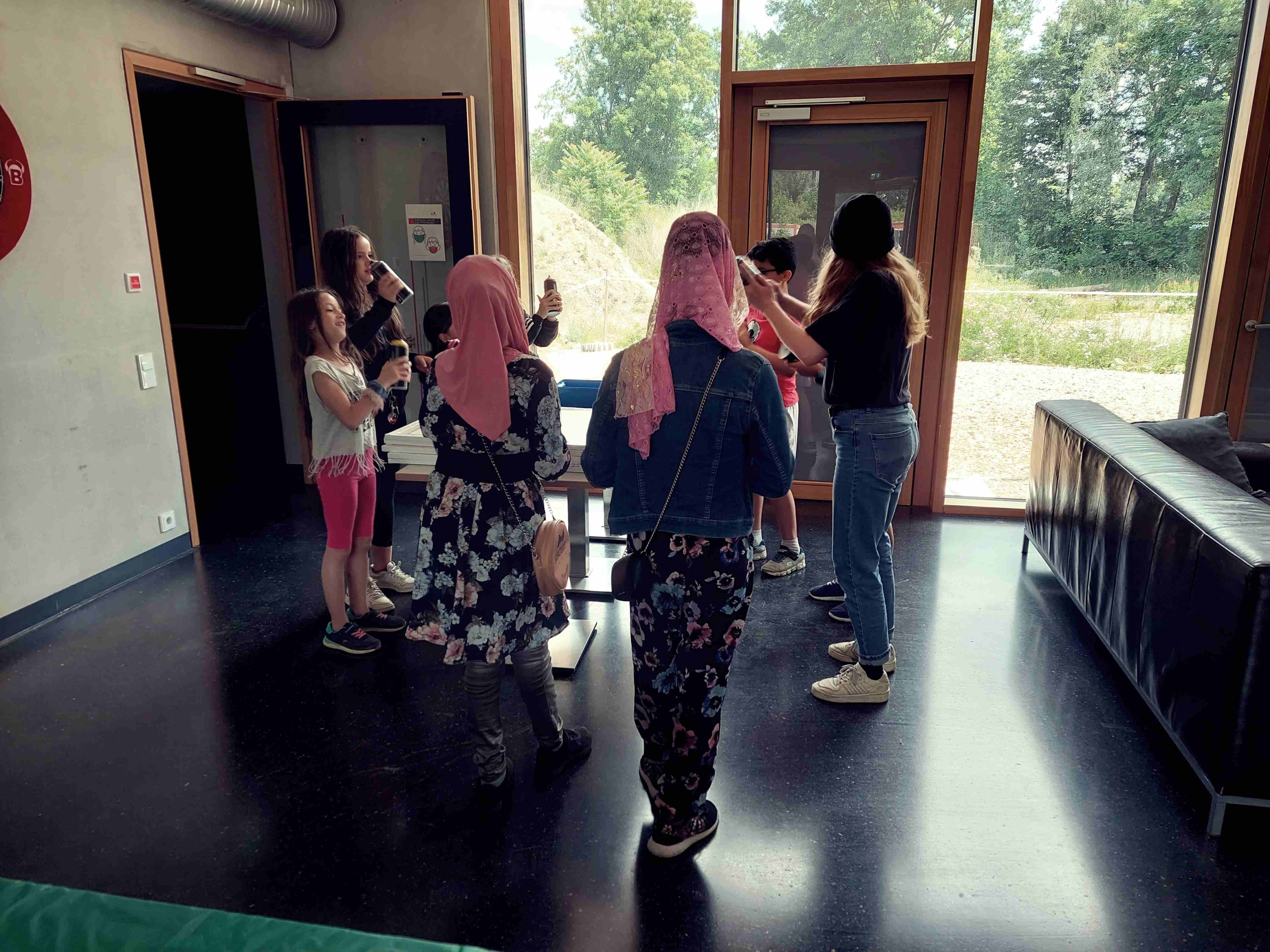 Auf dem Foto befinden sich mehrere Kinder mit einer Pädagogin im Foyer des Jugendzentrums Guericke.