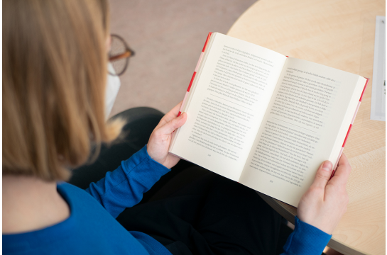 Fotografie - Eine Person liest ein Buch.