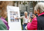 Fotografie: Eine Frau erklärt eine Denkmaltafel. (C) Bilddokumentation Stadt Regensburg