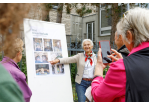 Fotografie: Eine Frau erklärt eine Denkmaltafel.