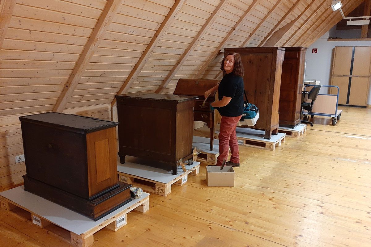 Fotografie: Eine Möbelrestauratorin reinigt historische Schränke und Kommoden vor dem Verpacken.  