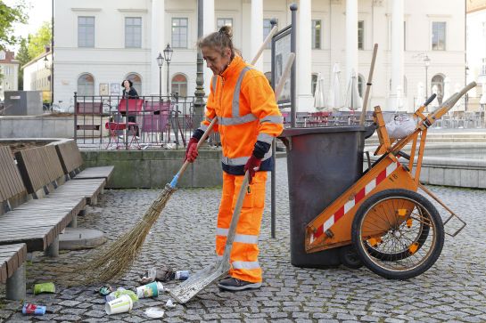 Mit Besen und Schaufel wird der Müll zusammengekehrt und in der Tonne entsorgt.