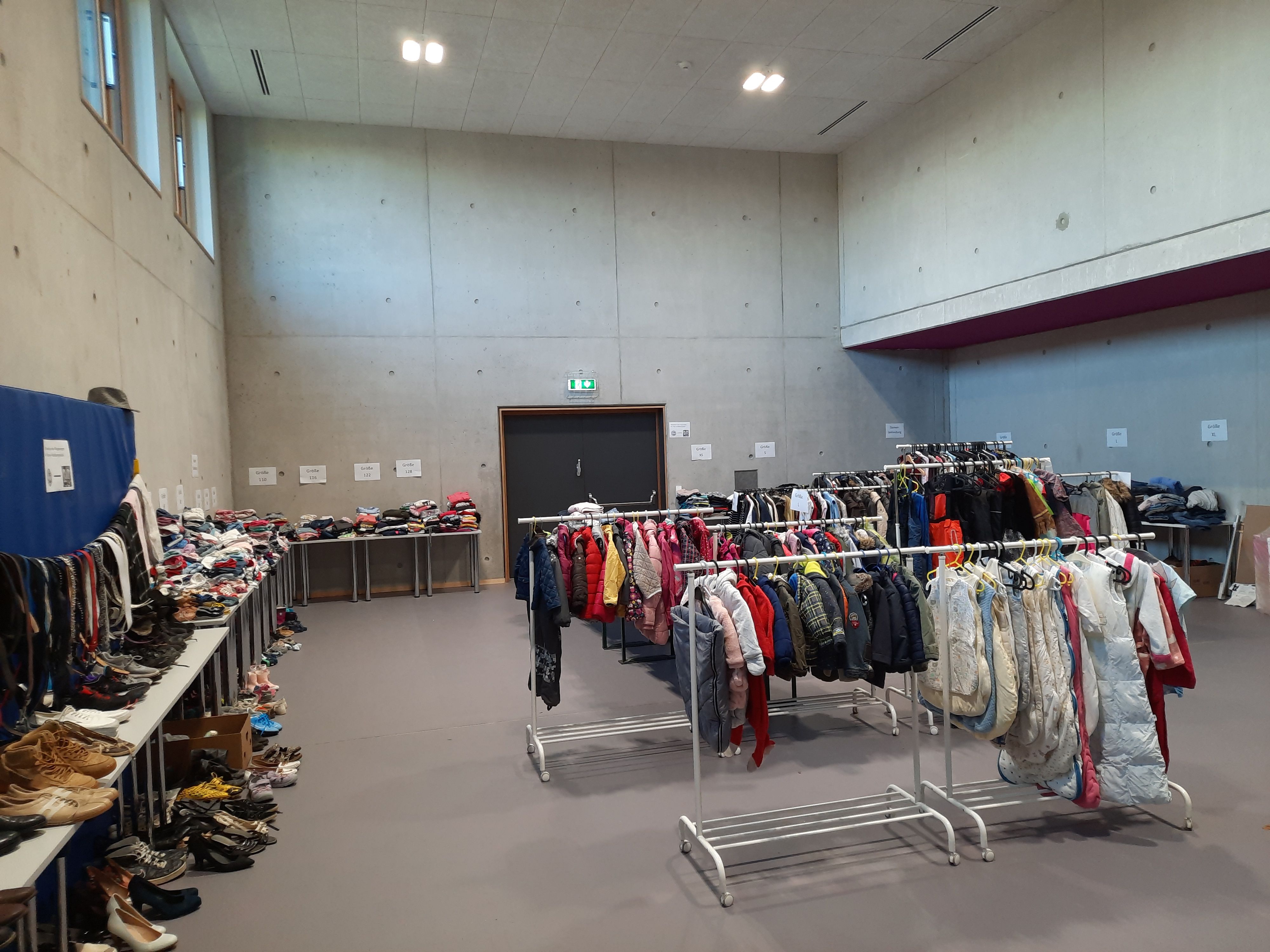 Fotografie - große Halle mit Tischen und Kleiderständern voller Klamotten