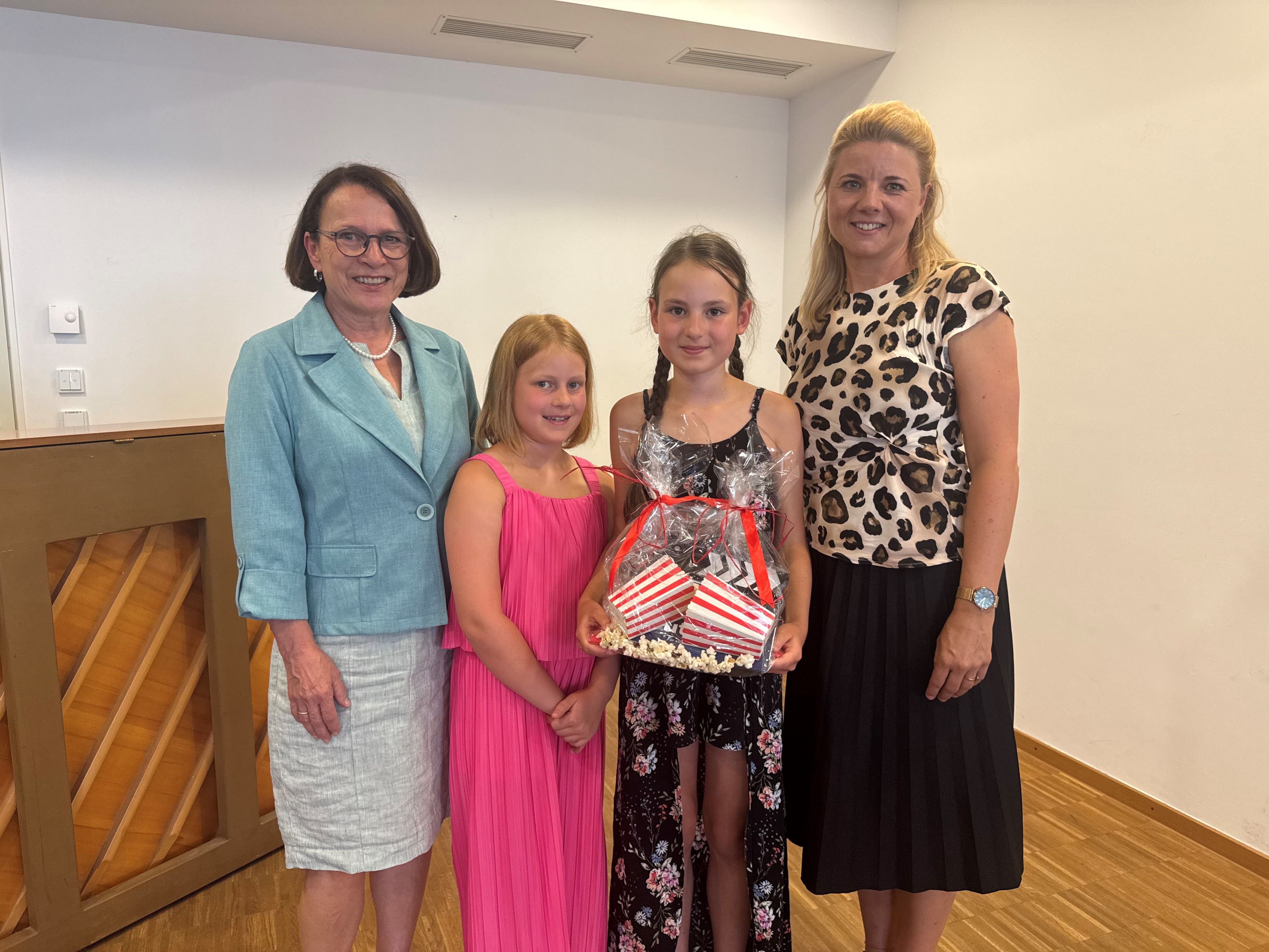 Fotografie – Oberbürgermeisterin Gertrud Maltz-Schwarzfischer und Melanie Brunner vom Amt für allgemeine Stiftungsverwaltung bedankten sich bei Hauptdarstellerin Nika Scheuerer und ihrer Schwester mit einem Präsent. 