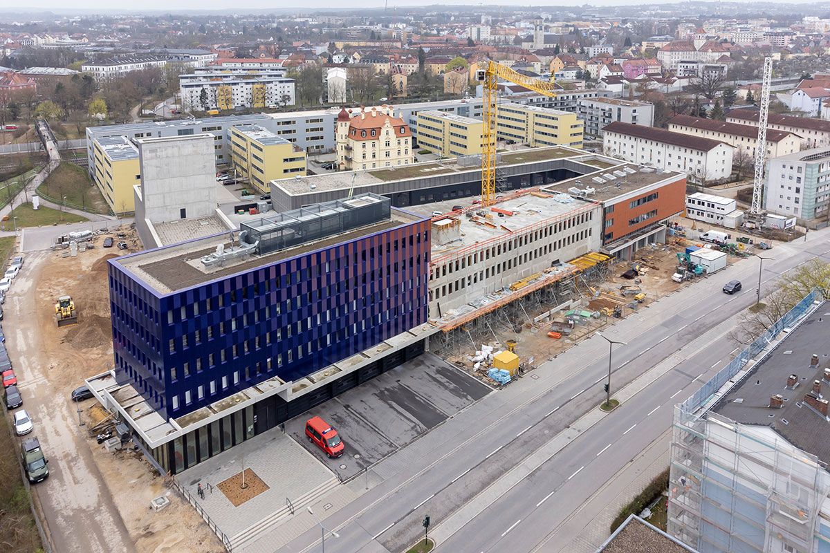 Fotografie - Rohbau der Fahrzeughalle mit Obergeschossen zwischen dem Altbau (rechts) und dem Neubau (links), im Hintergrund Richtung Süden Wohnbebauung 