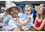 Fotografie: Ein Mann trägt seine Tochter auf dem Arm und hat ihr als Lärmschutz Kopfhörer aufgesetzt.