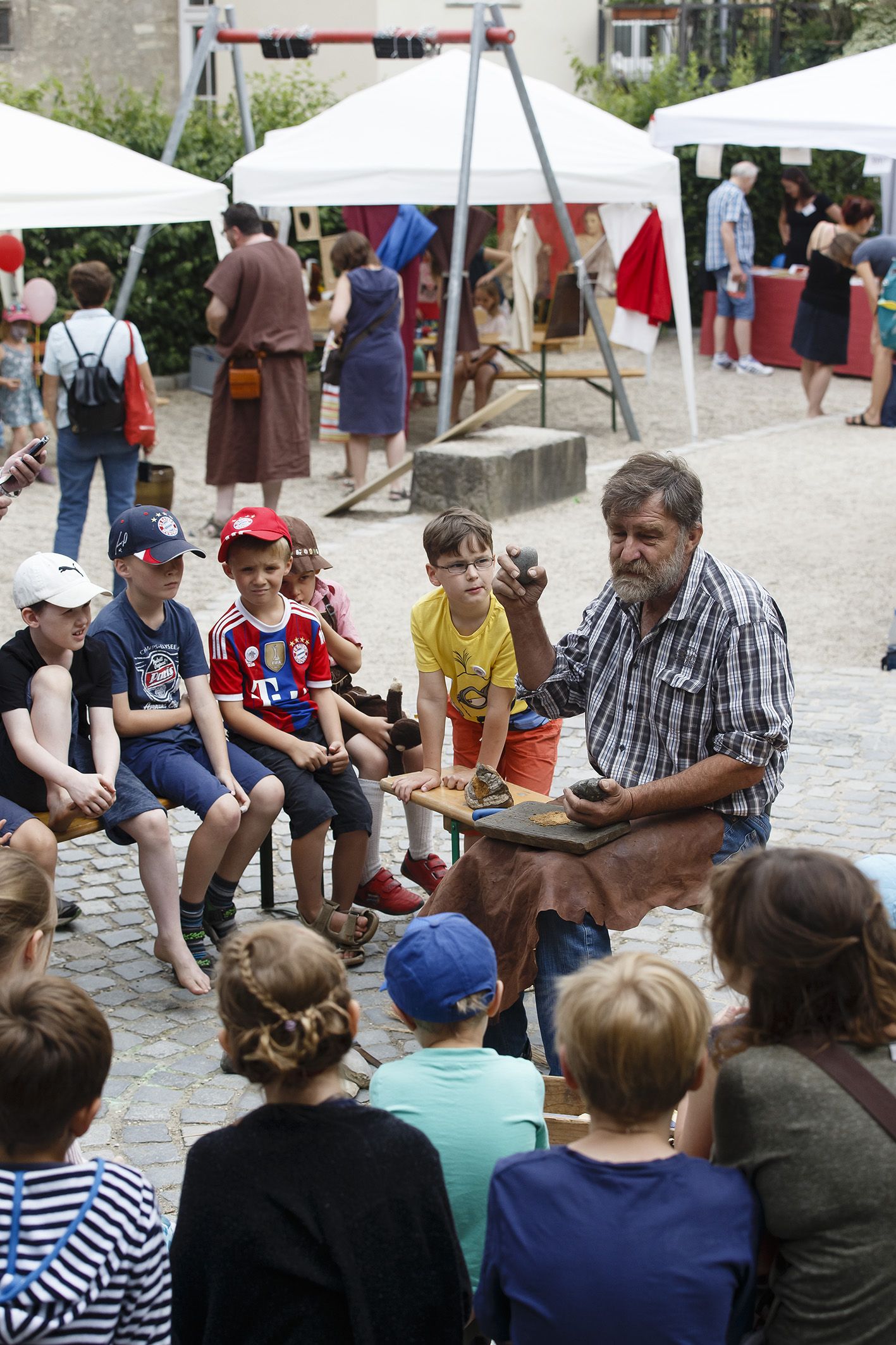 Fotografie: Ein Mann erklärt Kindern einen Stein.