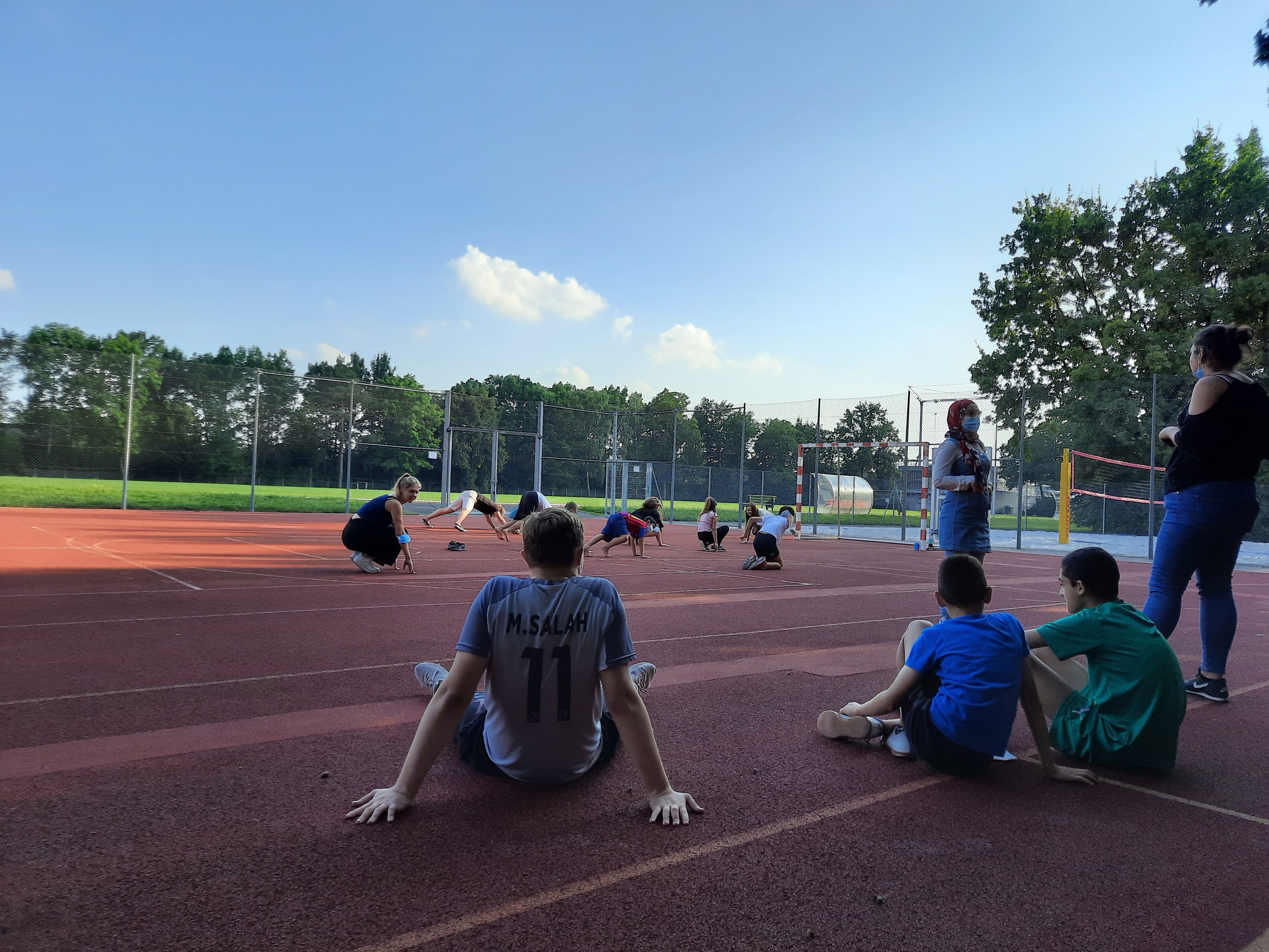 Es sind mehrere Personen auf einem Sportplatz zu sehen.