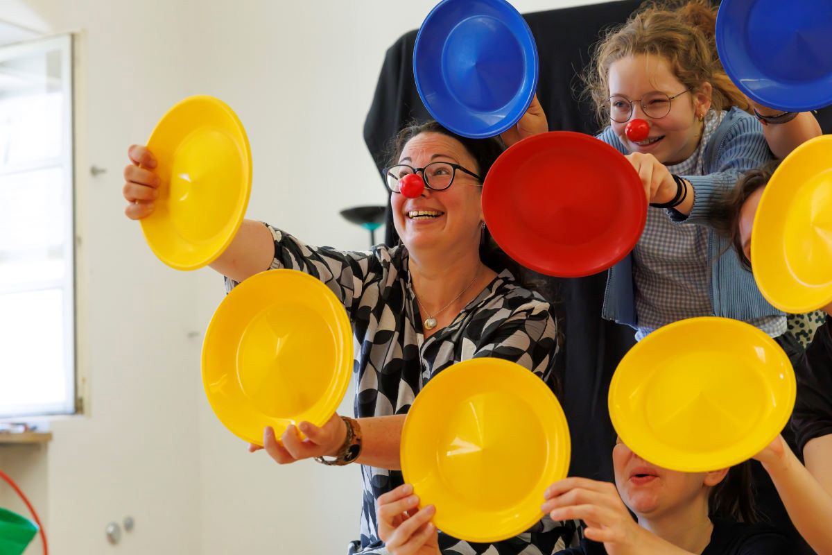 Fotografie: Clown Szene mit Teilnehmer mit Clown Nase und bunten Tellern
