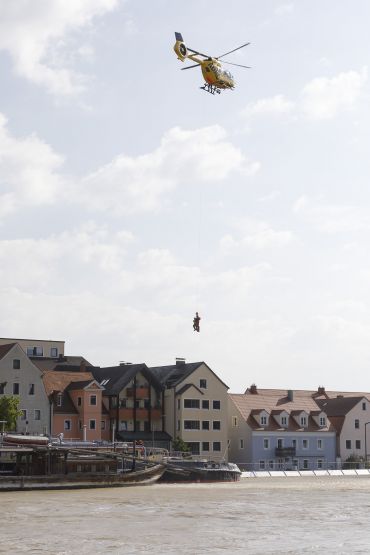 Fotografie: Zwei Personen werden von einem Hubschrauber auf ein Schiff hinuntergelassen.