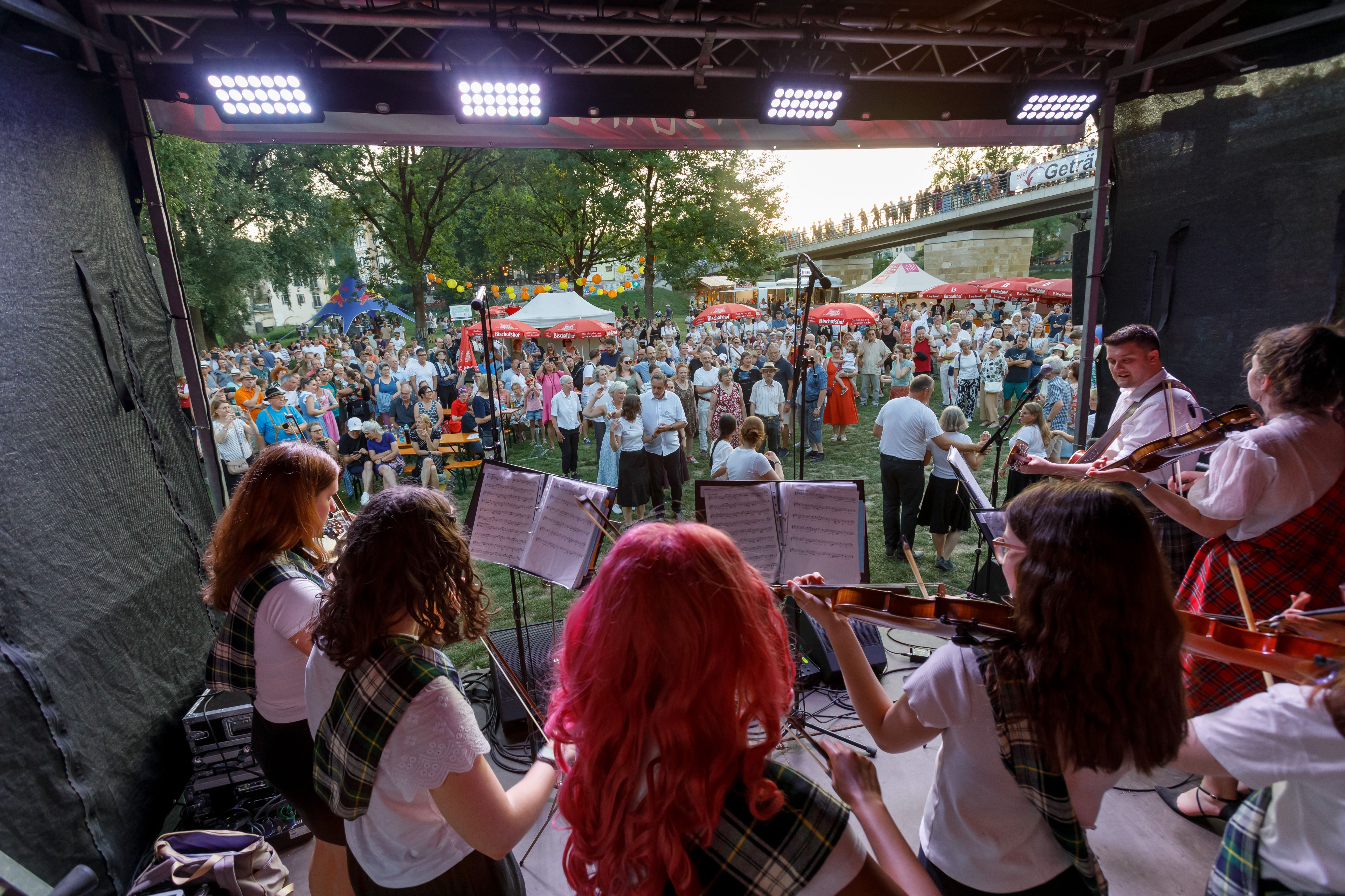 Fotografie: Musizierende Musikgruppe aus Aberdeen auf der Bühne vor tanzenden Besuchenden auf der Jahninsel
