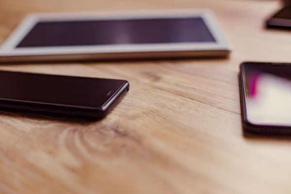 Fotografie: Smartphones und ein Tablet liegen auf einem Tisch.